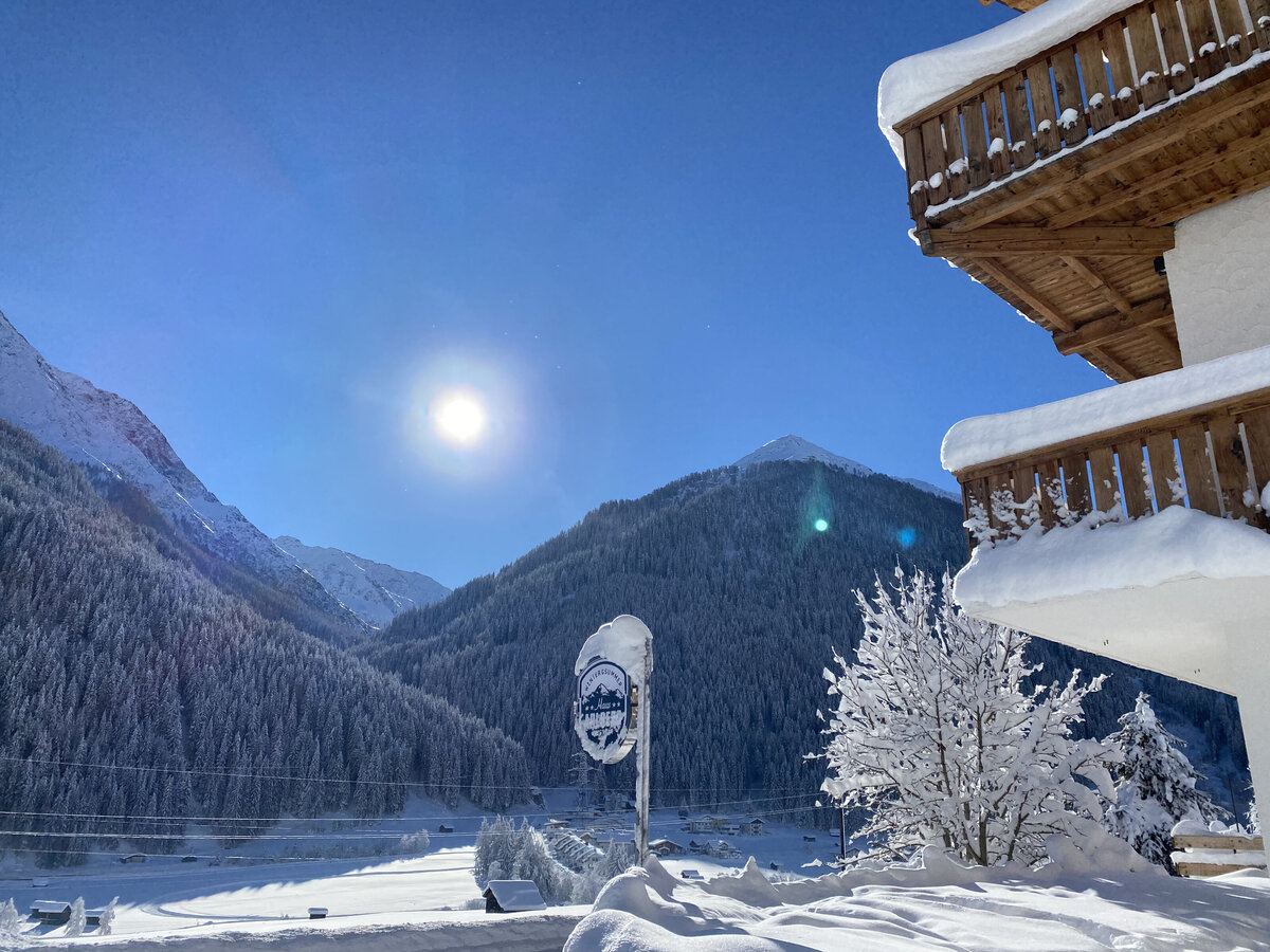 Sfeervolle woonkamer met open haard, comfortabele banken en rustieke houten afwerking in Haus Arlberg.