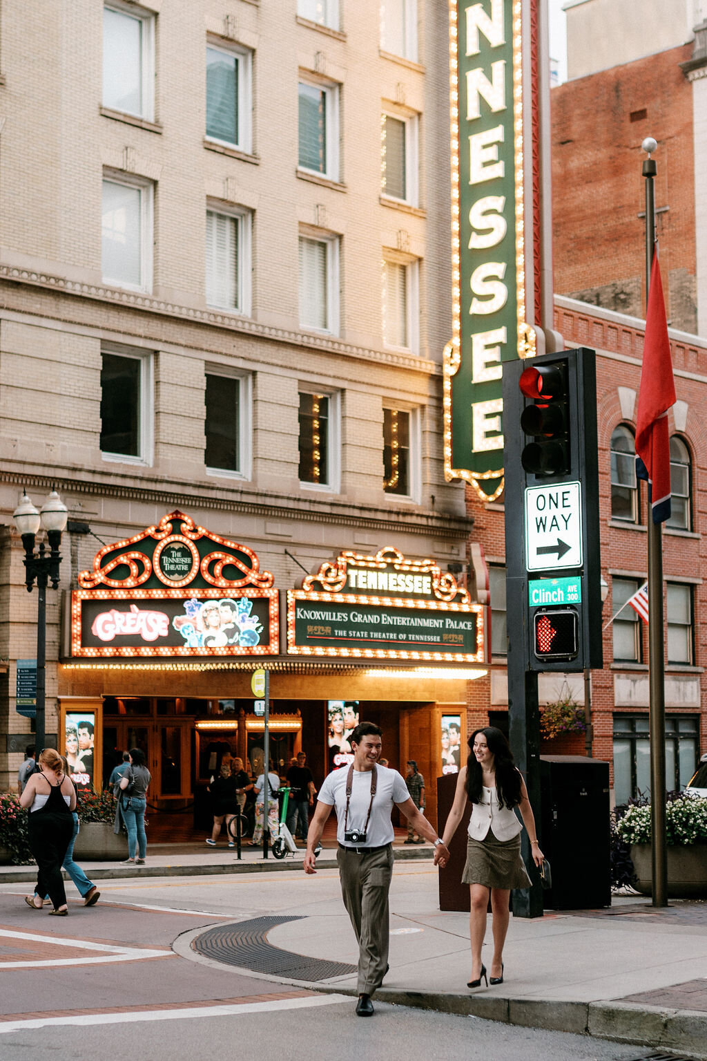 a couple walks across the street in front of the tennessee sign on gay street in knoxville tennessee