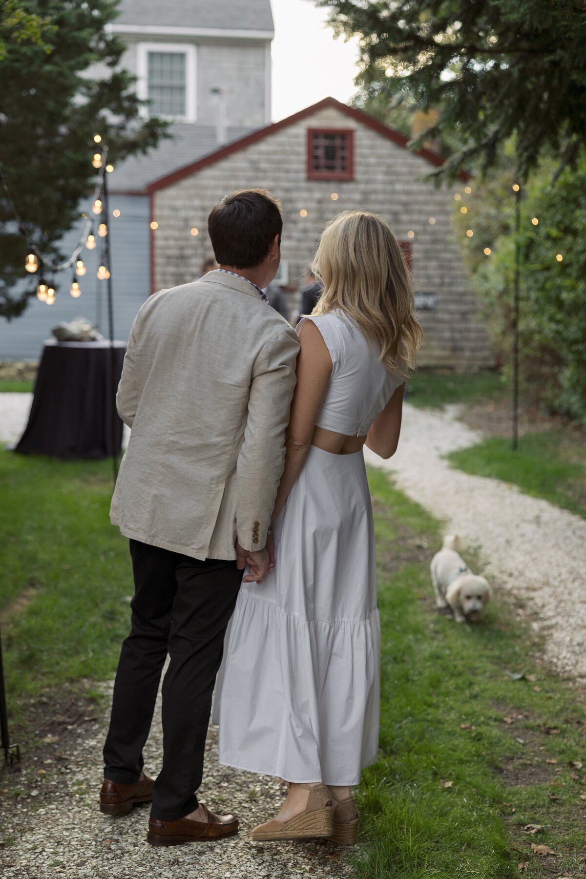 Bride and Groom hold hands in backyard reception of Nantucket wedding.
