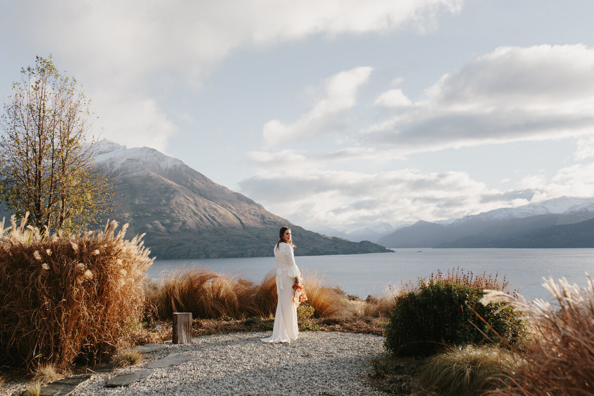 The Lovers Elopement Co - bride looks out over Queenstown lake to mountains in the distance