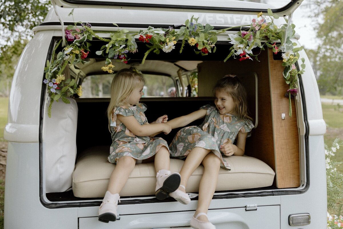two little girls sit in the back of a VW bus for family photos