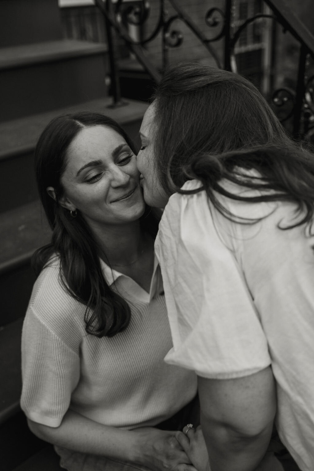 LGBTQ+ couple holding hands on New York City steps during their engagement session, captured by NYC wedding and elopement photographer Dom Augustine.