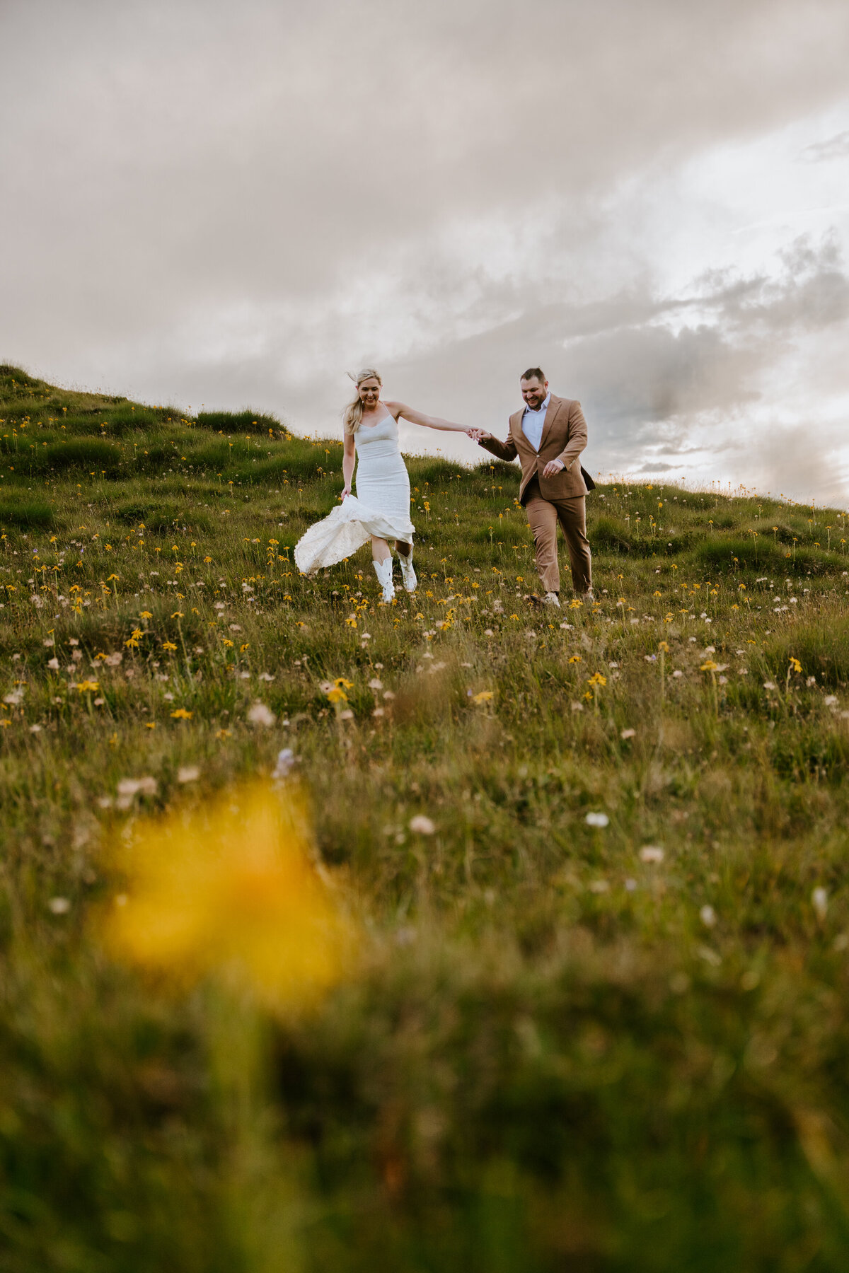 Couple running through wildflower meadow in the Dolomites