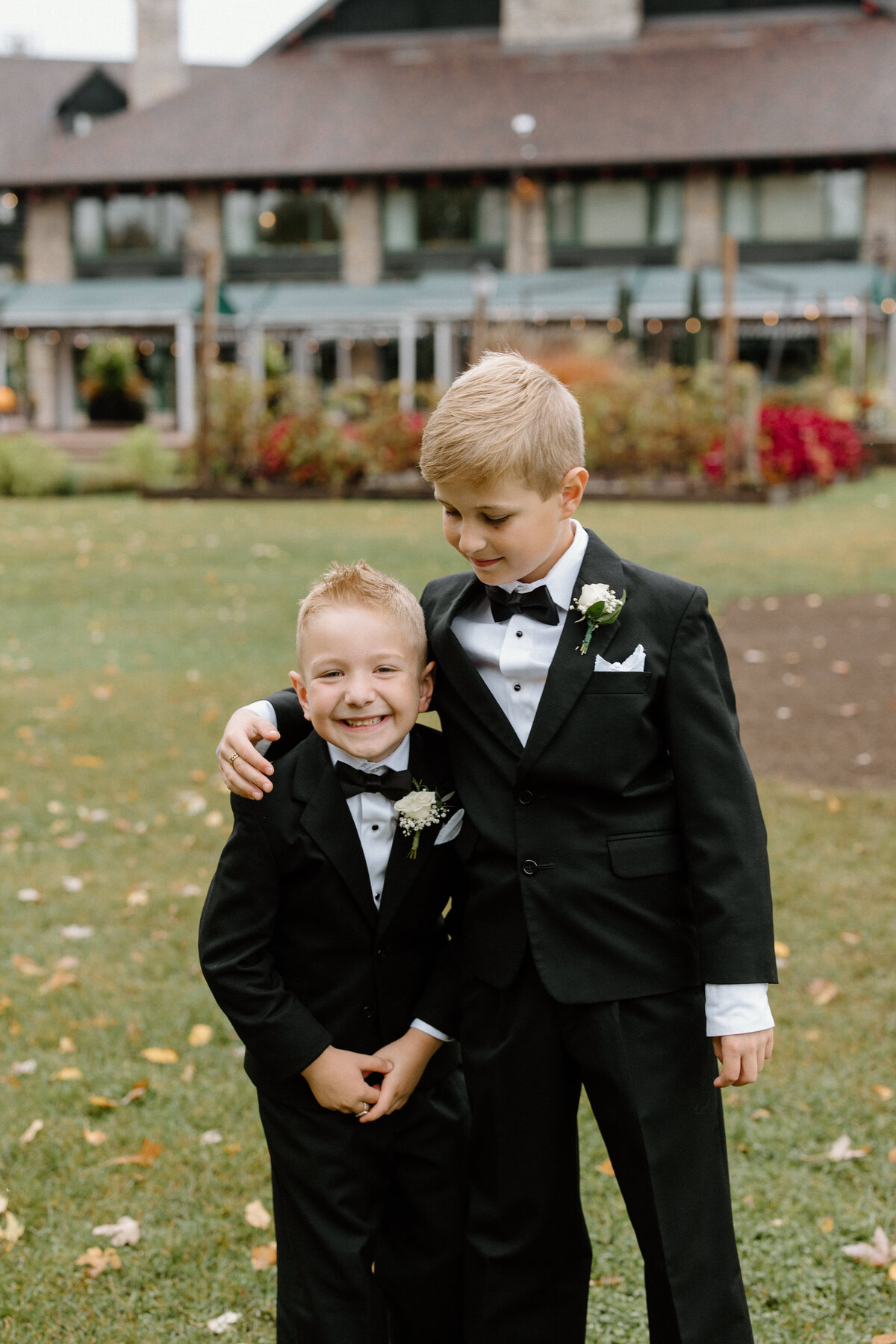 Two boys smiling in suits at a wedding ceremony
