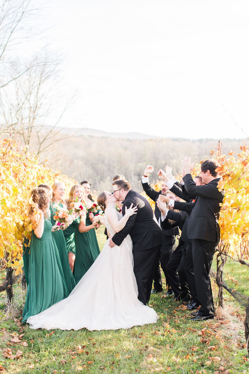 Bride and groom kiss while wedding party cheering on them
