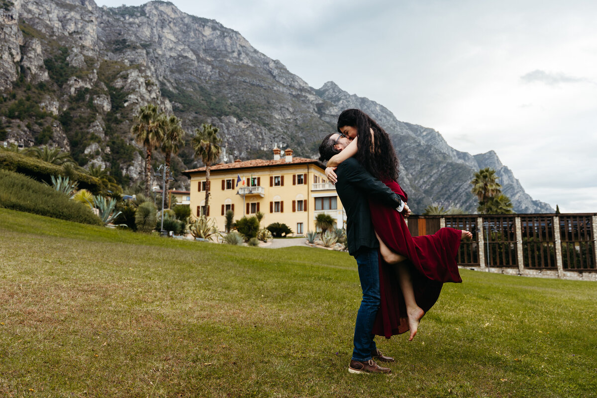 Man spinning partner on grass with mountains in the background