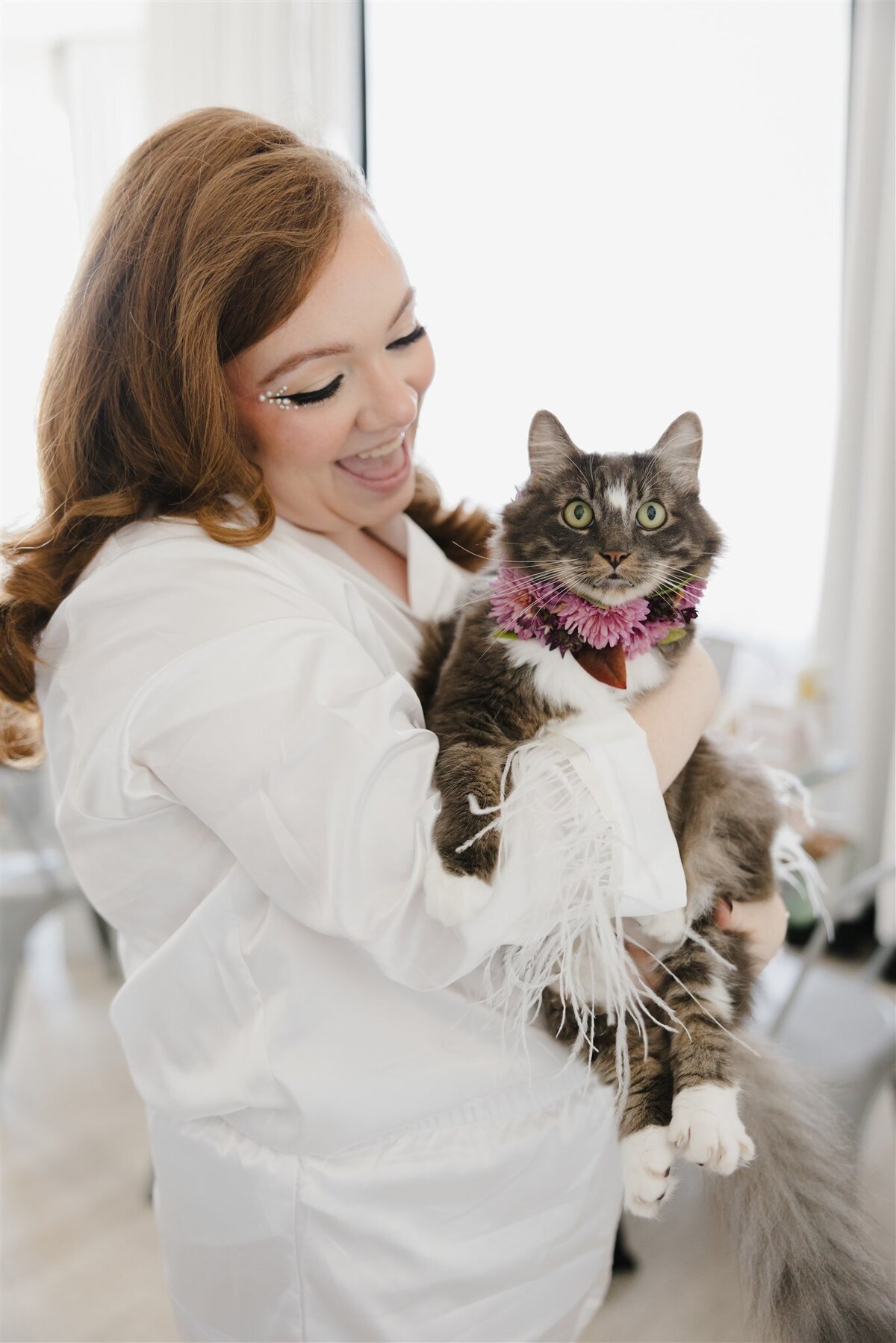 Bride holding her cat who is wearing a floral collar on her wedding day