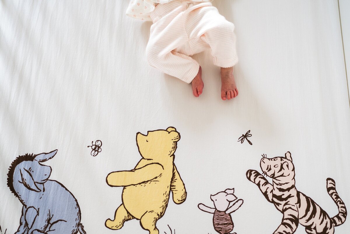 Newborn feet on a classic winnie the pooh crib sheet