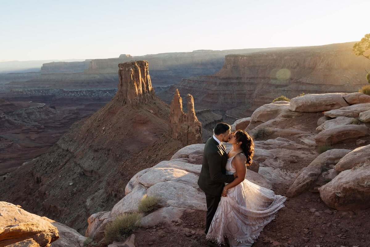 a couple stands facing one another as the sunsets at Marlboro Point during their Moab Elopement day