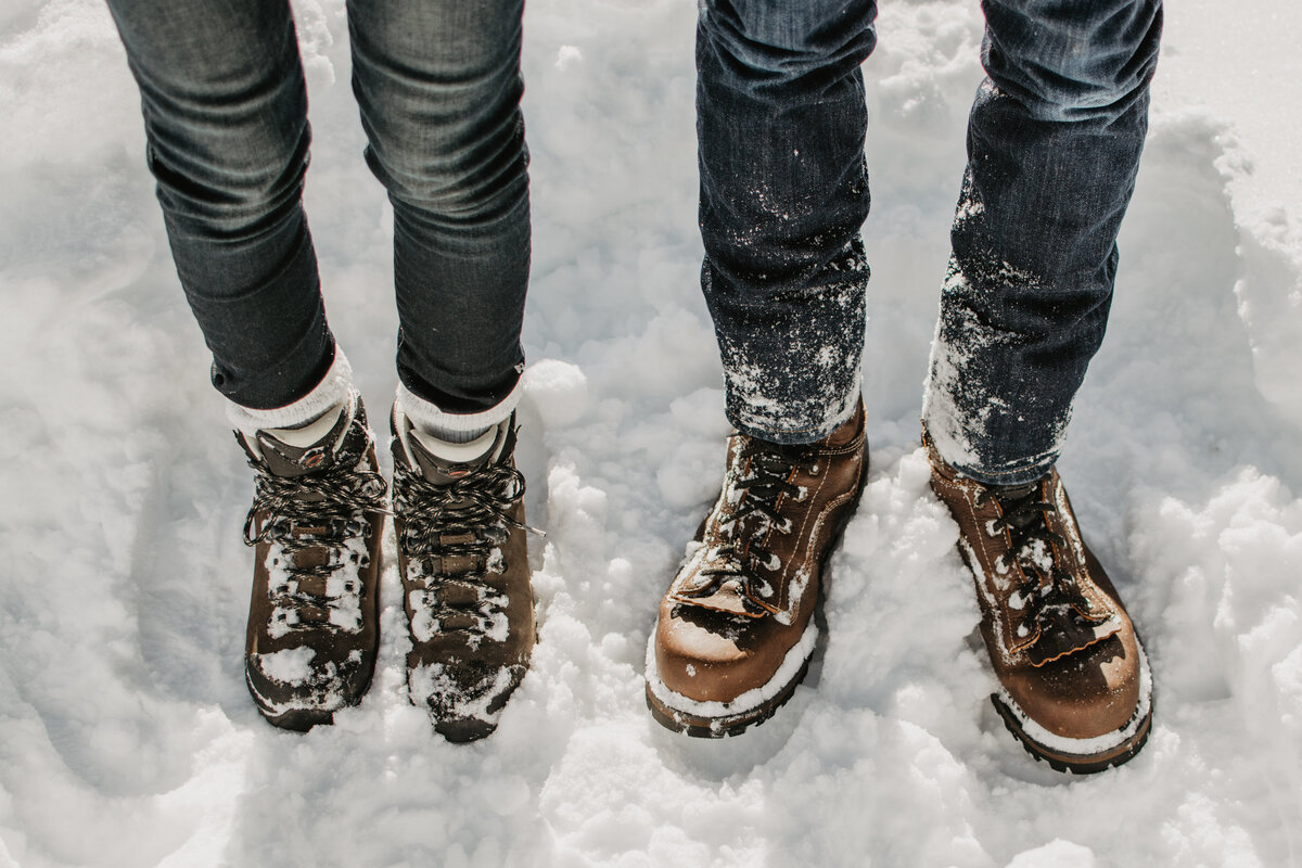 winter engagement session with man and woman's boots in the snow