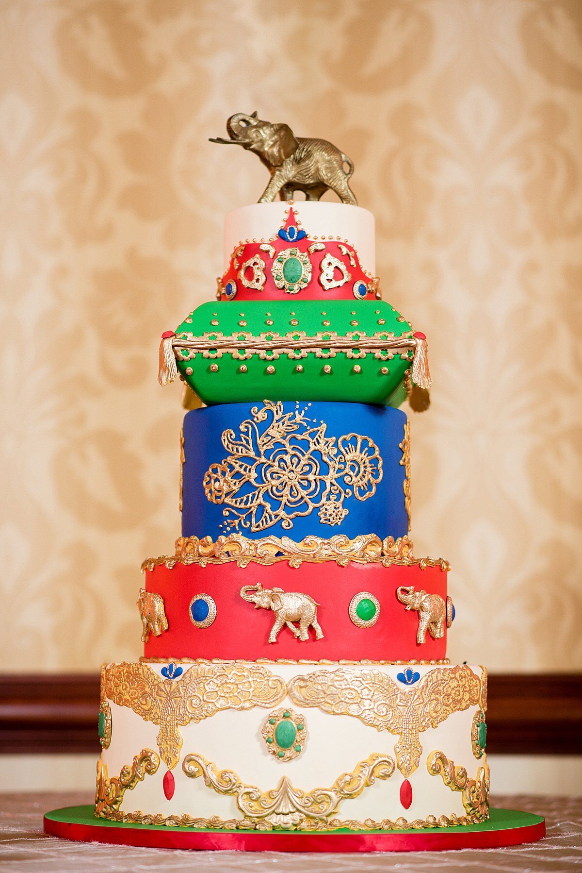 Elaborate wedding cake for an Indian Wedding in Nashville. A white, red, blue and green Hindu wedding cake  topped with a gold elephant and gold mandala details in Nashville.