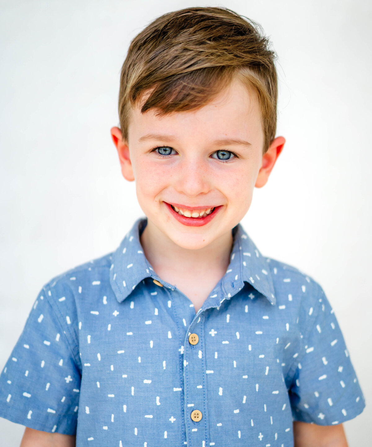School portrait of young boy with bright smile on white backdrop — S. Reed Photography