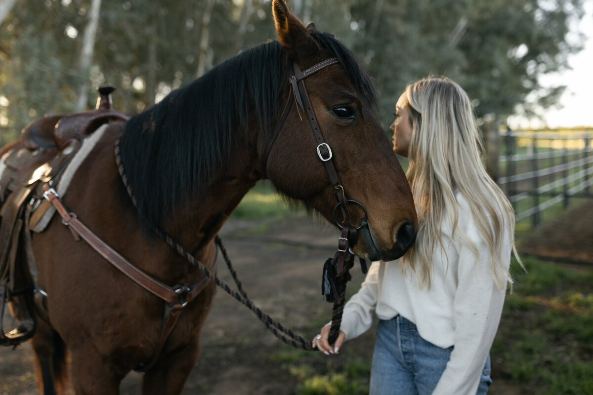 Rustic lifestyle branding photo of a woman holding a brown horse’s reins at golden hour, captured outdoors with a natural, western aesthetic in South Carolina.