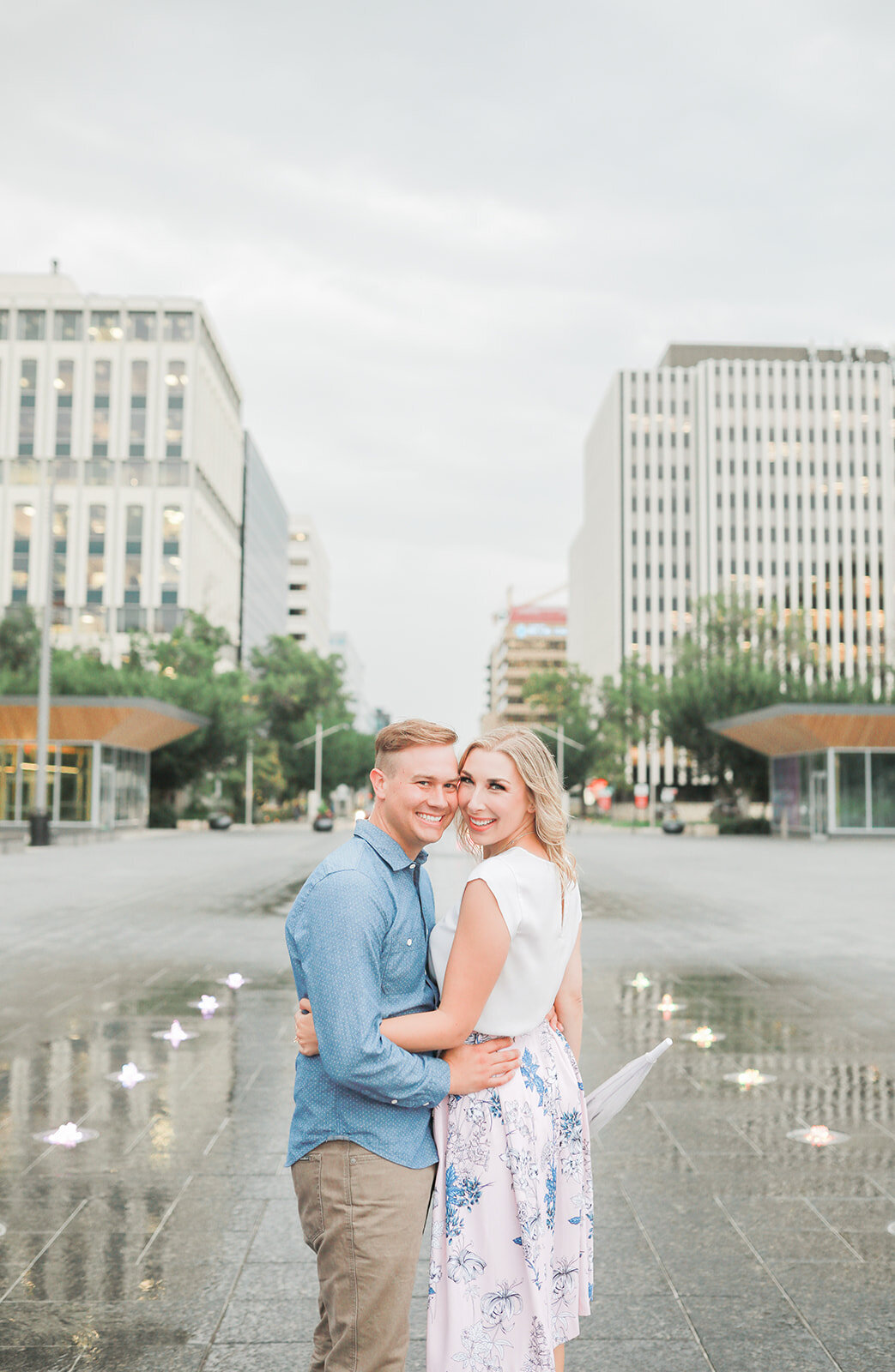 Couple holding each other turn to look at the camera behind them