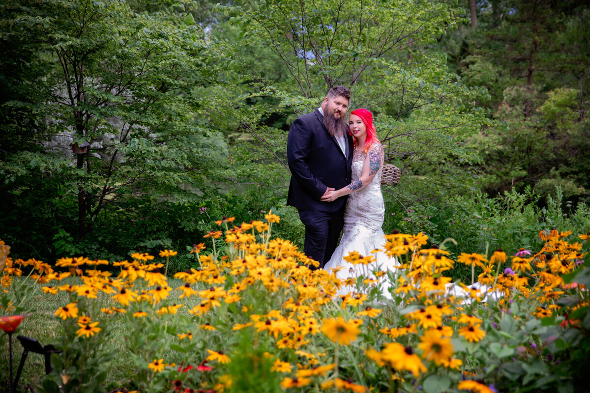 Bride and groom stand behind a field of sunflowers