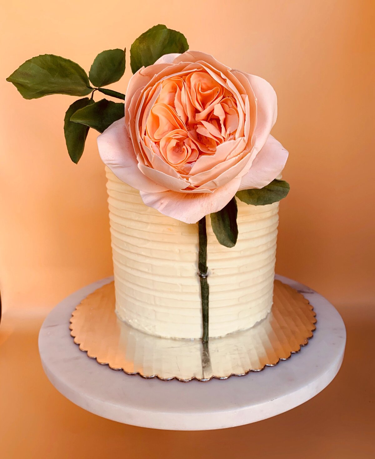 Single tier ivory buttercream cake with large peach Juliet rose