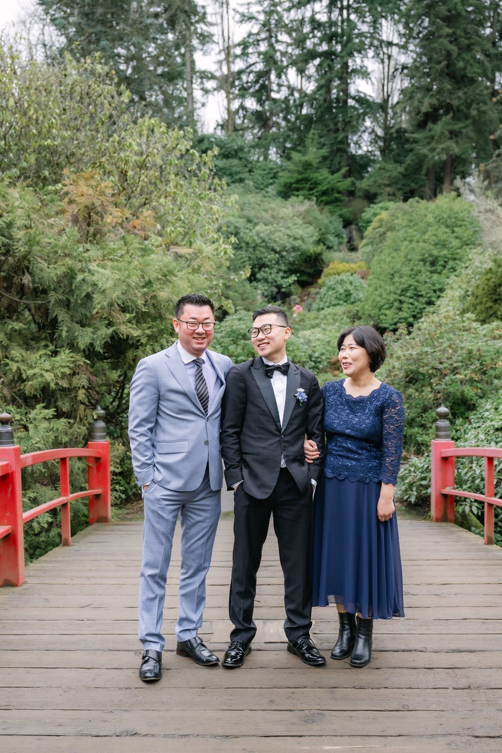 groom with mother and father on red bridge at kubota garden seattle