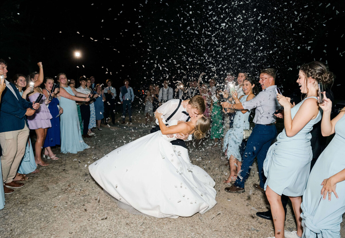Groom leaning bride back for a kiss during wedding exit
