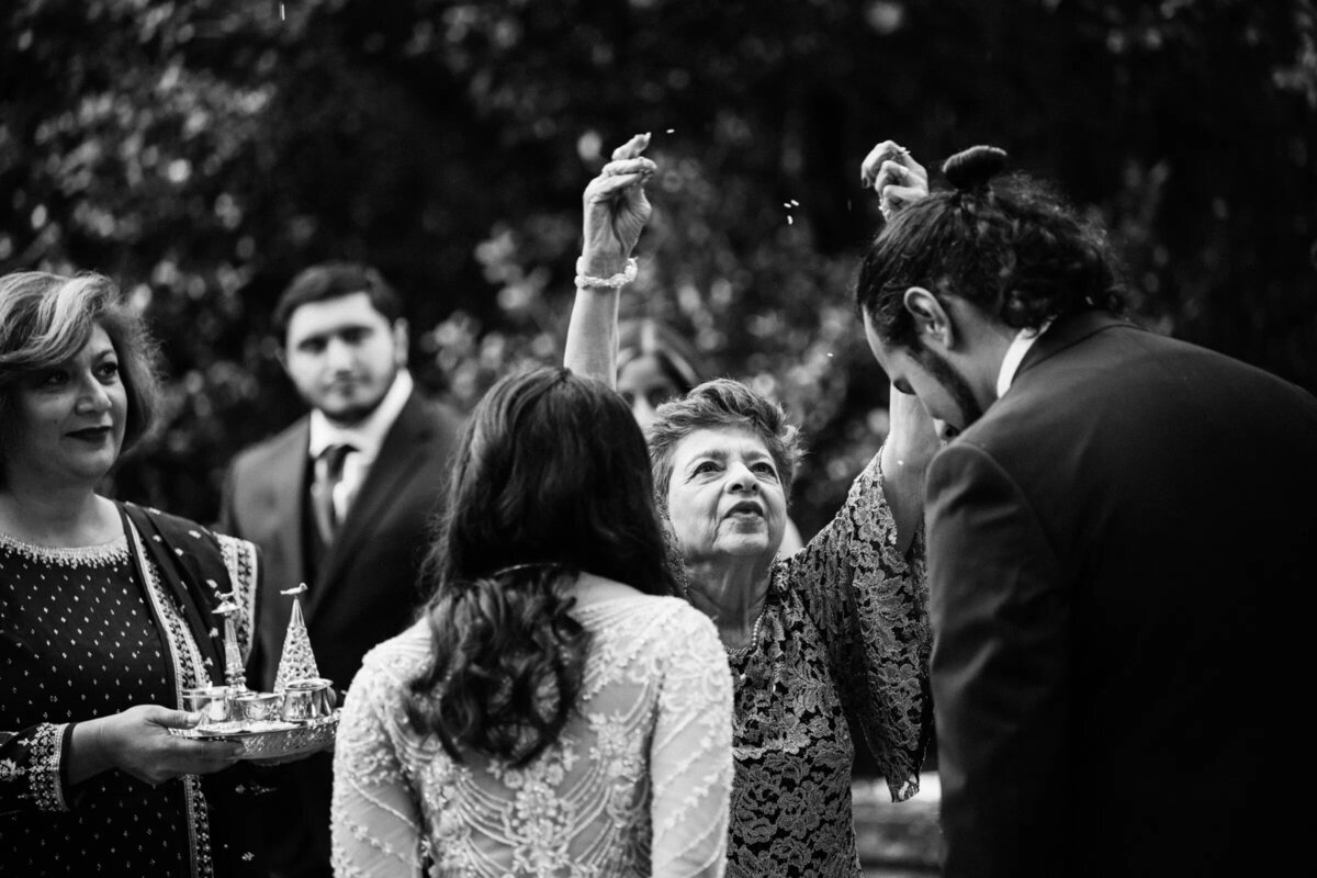 A woman raising her hands up in front of a bride and groom.