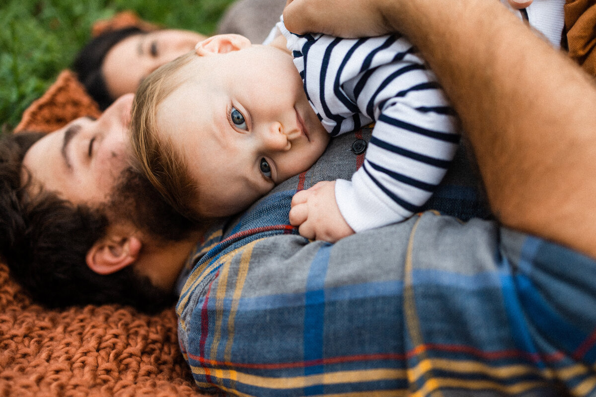 Son laying on father's chest in a field