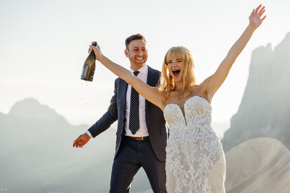Couple popping champagne at sunrise in the Dolomites