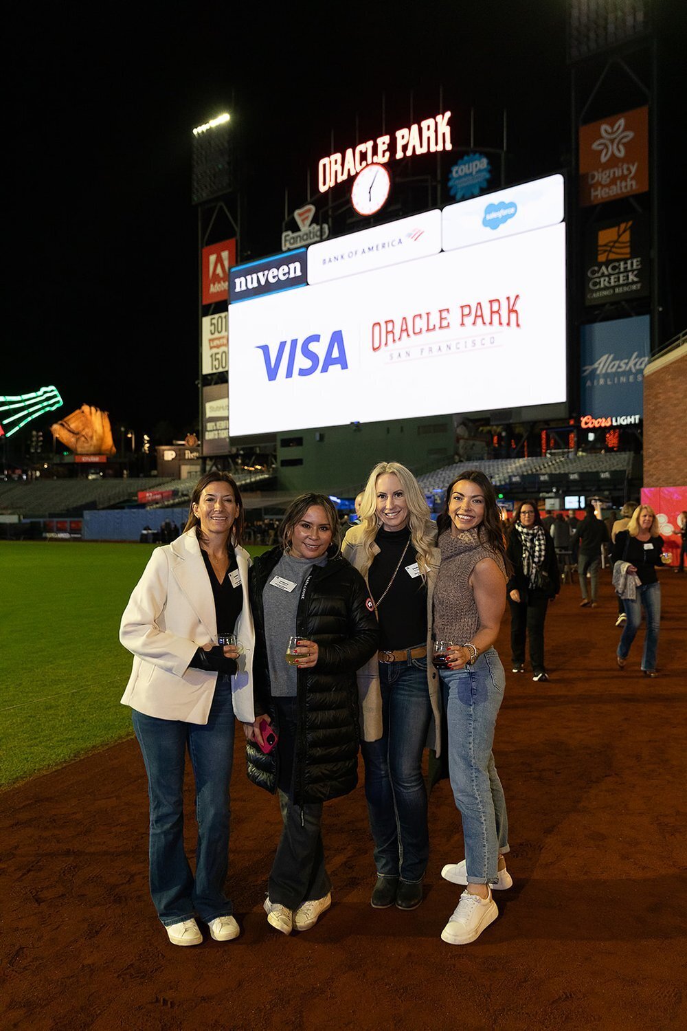 4 women at oracle park on the field holding drinks