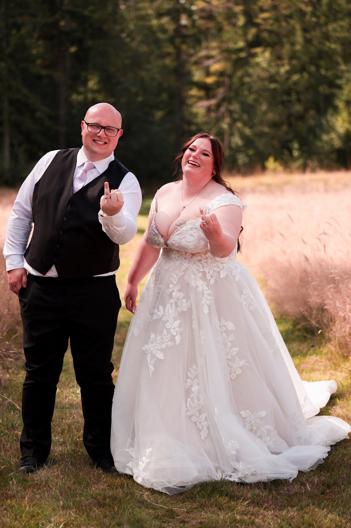 plus size bride and groom share a funny wedding photo in a large sunny field during their wedding