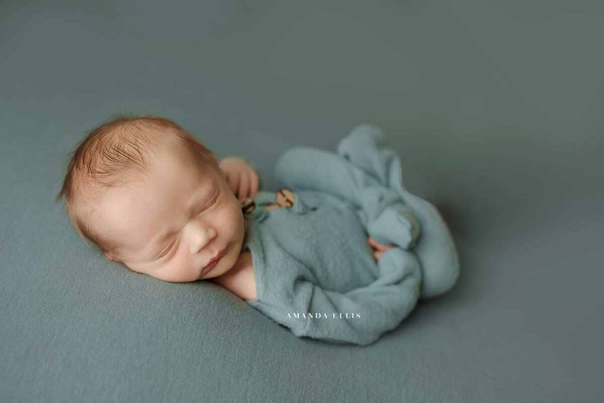 Newborn portrait of baby in pastel blue set and onesie