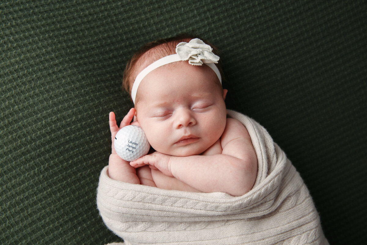 Newborn baby portrait with baby holding a golf ball