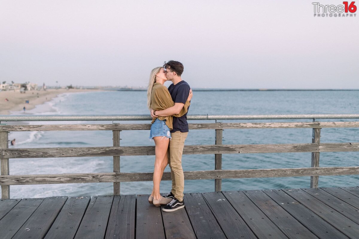 Engaged couple share a romantic kiss on the Seal Beach Pier