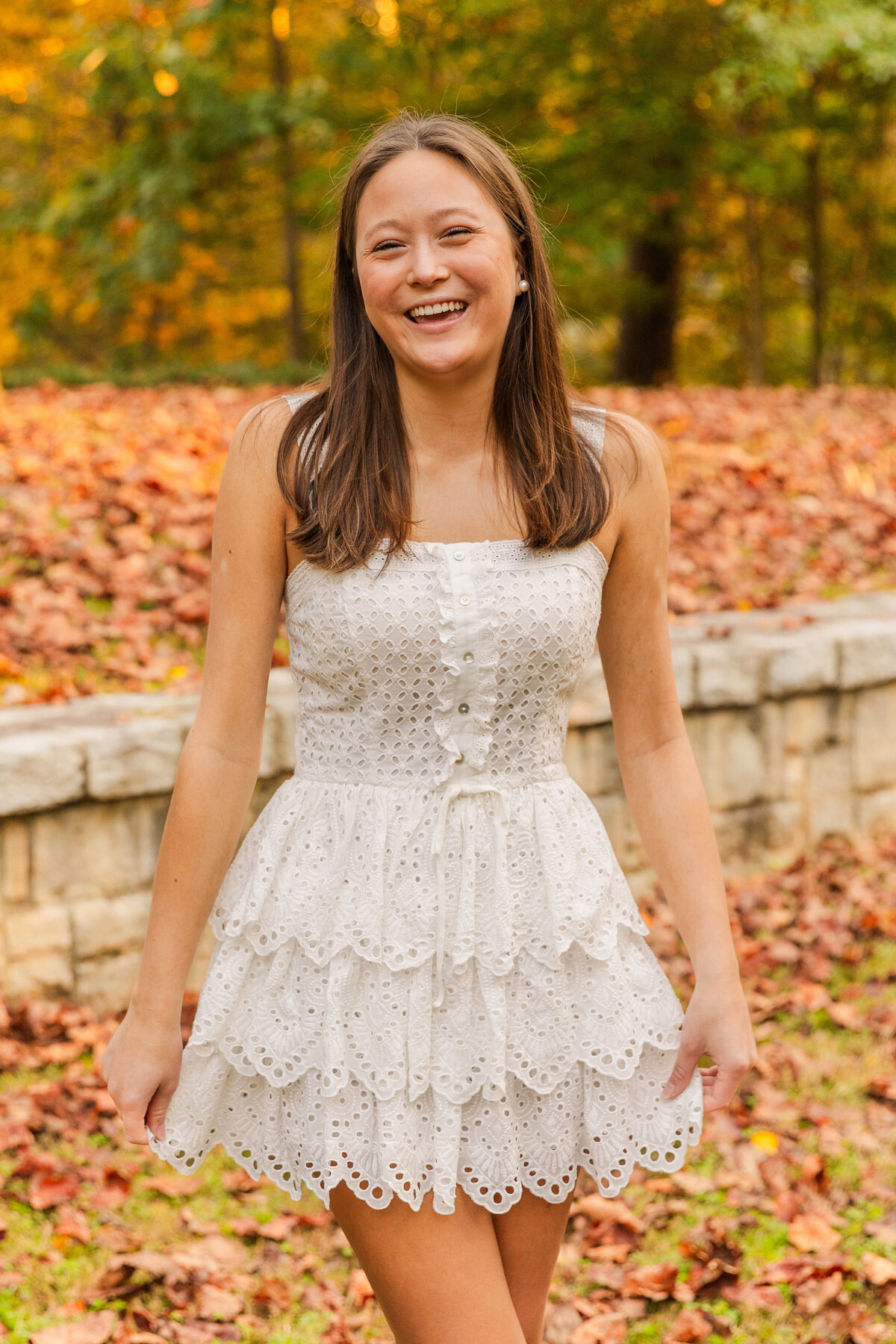 teenager girl laughing wearing white dress and laughing at the camera during portrait photo session