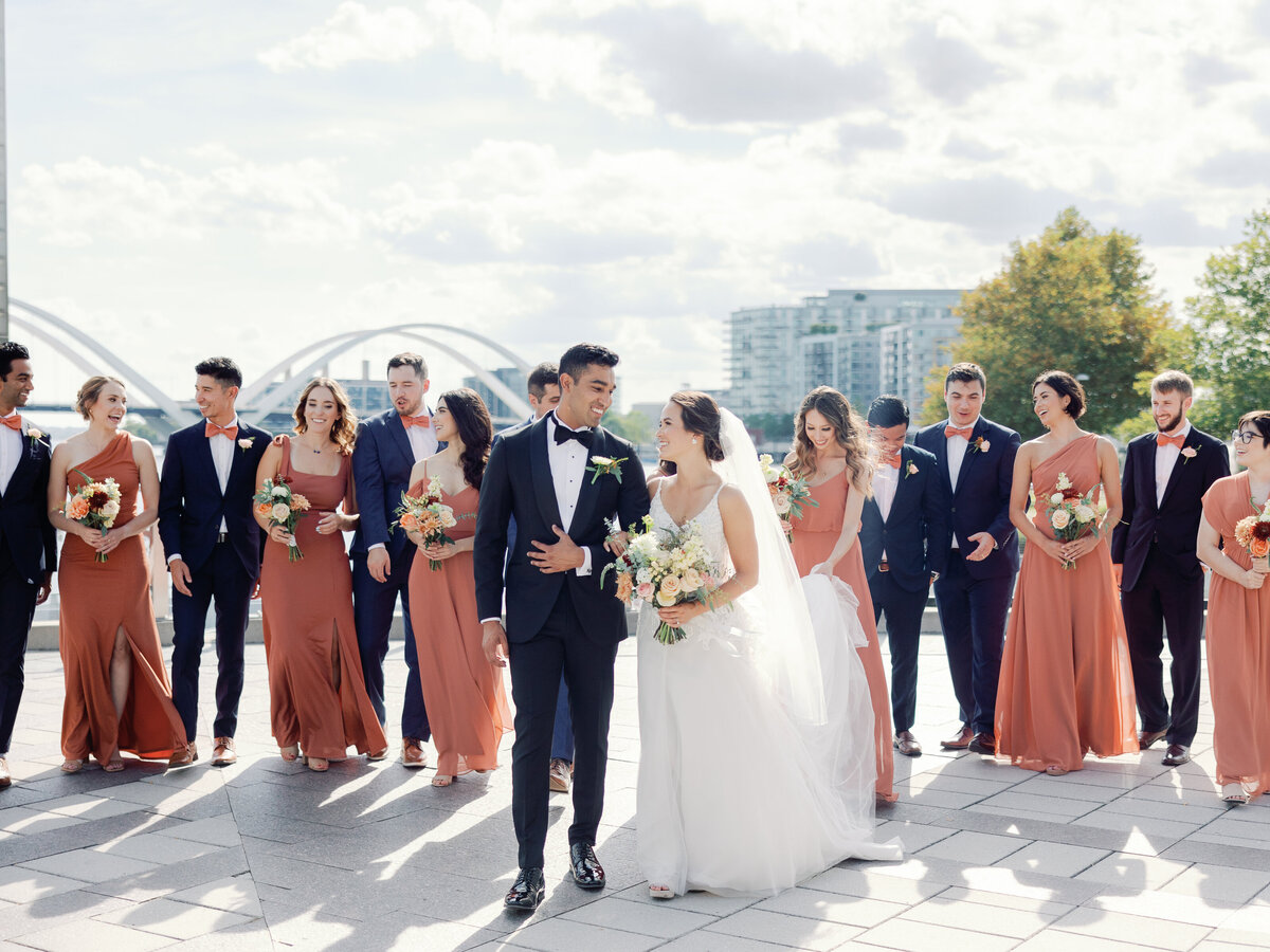 A bride and groom walks with their wedding party on the dock at the wharf in washington dc