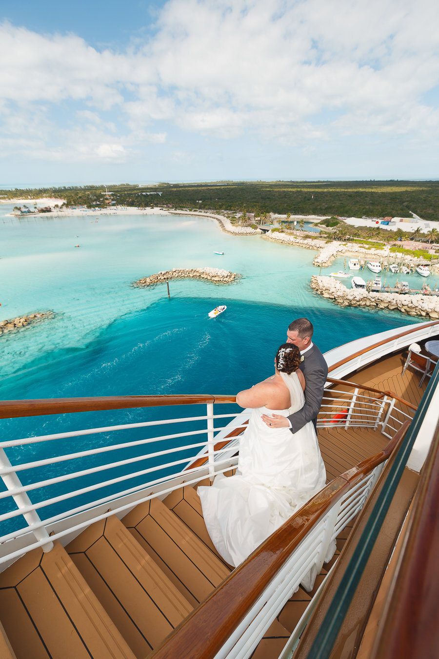 Bride and Groom embrace on stairs overlooking Disney's Castaway Cay