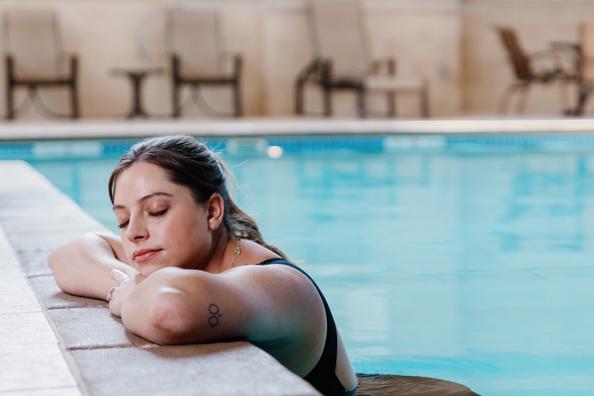 A person in a pool with their arms and head rested on the edge