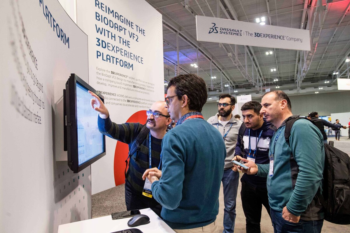 Engineers look interested  at monitor in the 3D Experience booth while a demonstration takes place