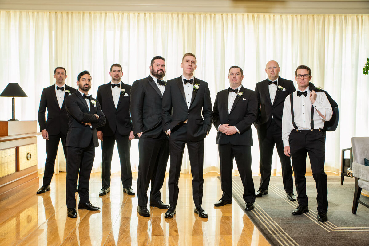 A group of men in tuxedos and bow ties are posing for a picture