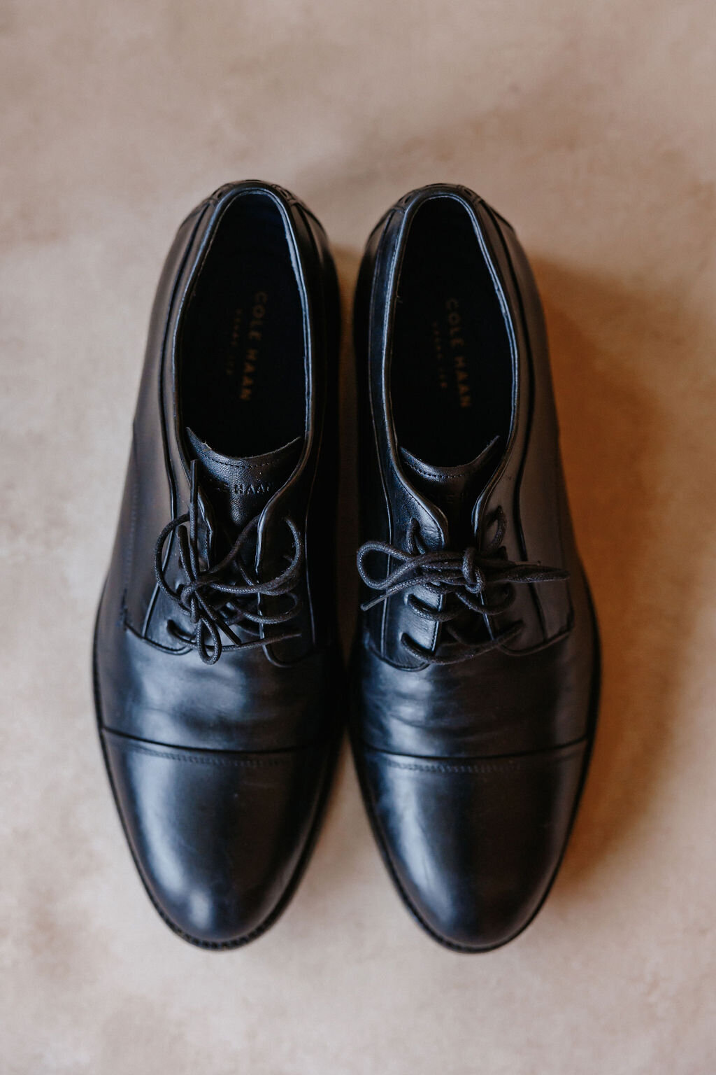 Groom detail photo of shoes on a neutral backdrop