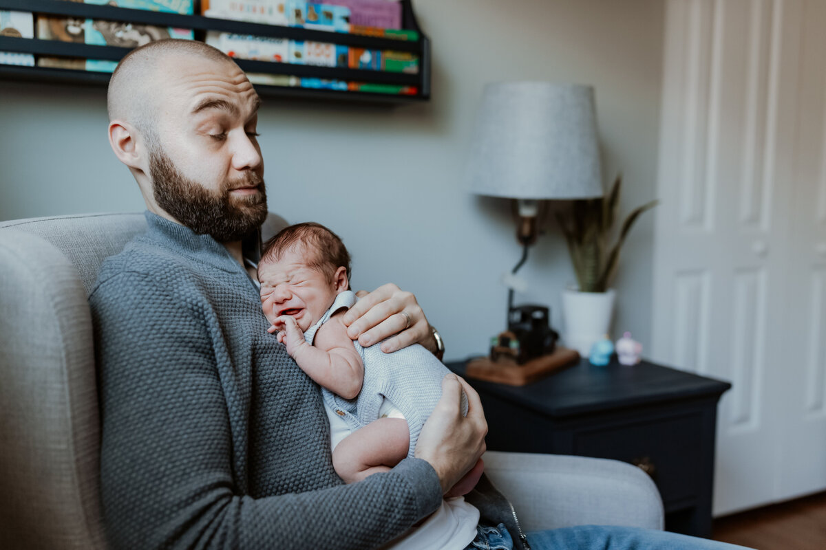 Dad surprised by newborn baby crying during in home photography session by Taylor Lynn Studios