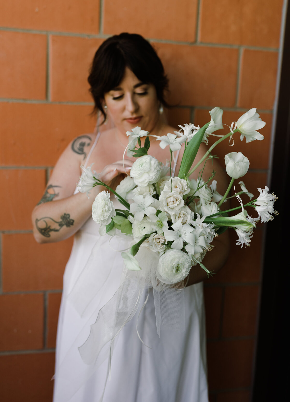 Bride wearing white gown holding bouquet of white florals