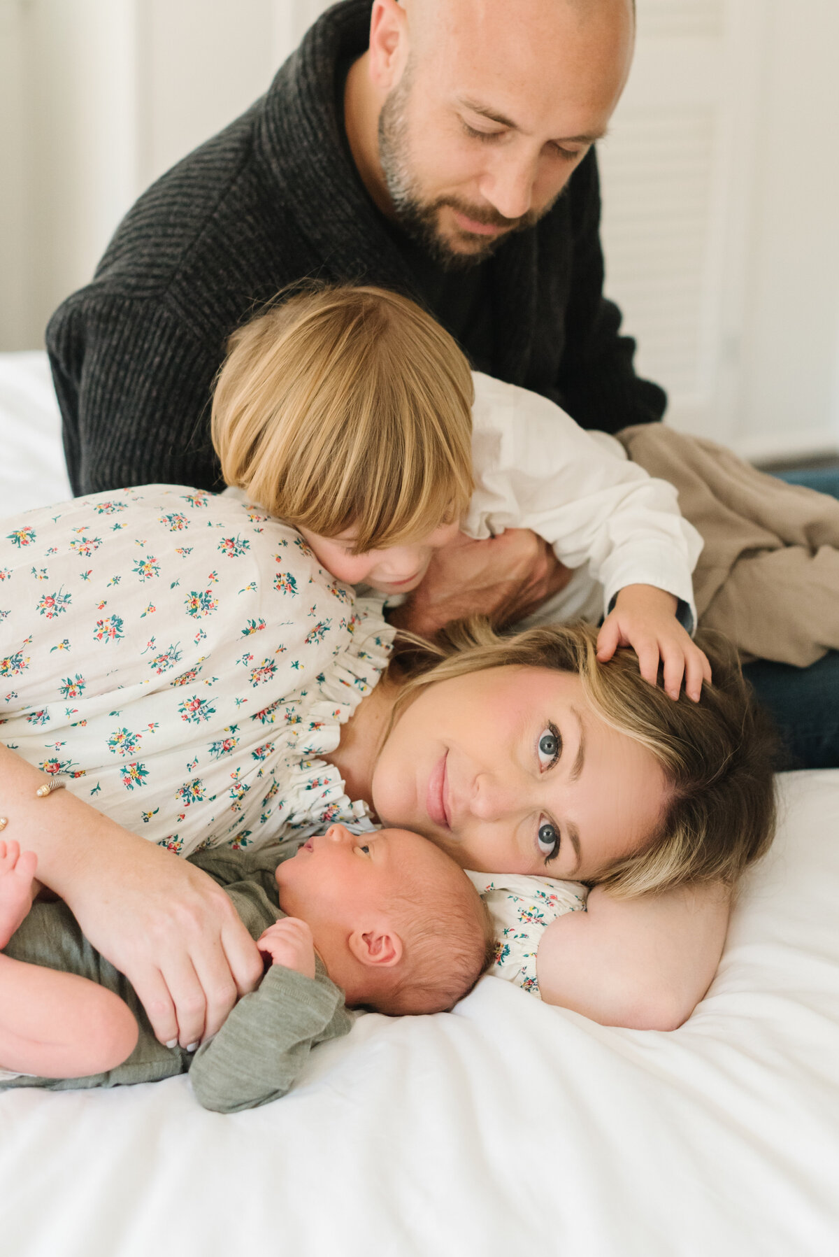 Mom looking at camera while newborn, toddler, and dad look at her - Washington DC Newborn Photographer