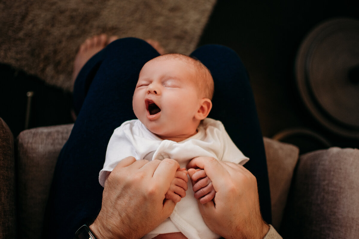 Dad holding baby girl on his lap while she yawns during a photoshoot in Chicago, IL