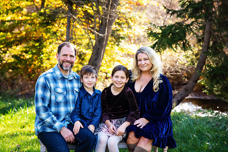 Beautiful family sitting in a bench in October for their fall family photo session in Jefferson NJ 