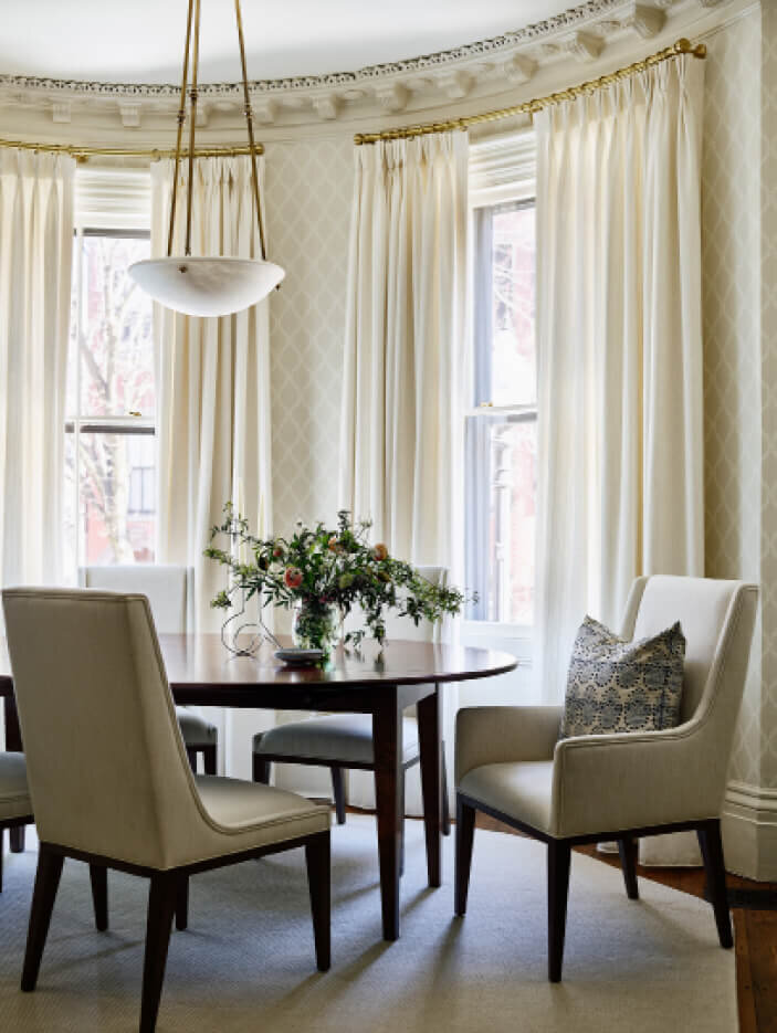 Classic Dining Room Design in a brownstone by Boston interior decorators features a traditional table, upholstered chairs, an alabaster pendant, and wallpaper.