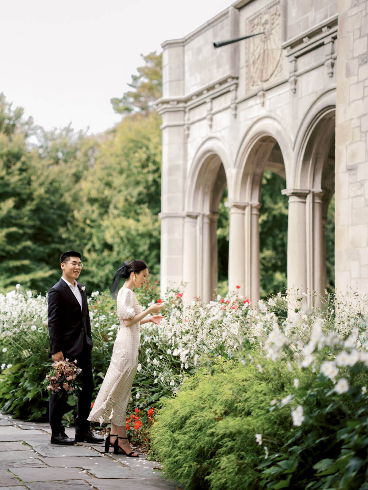 The engaged couple is gazing at the beautiful flowers outside Coe Hall at Planting Fields Arboretum, NY. Image by Jenny Fu Studio