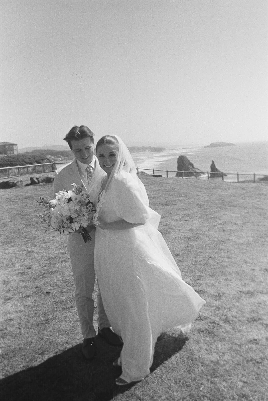 Black and white image of a bride and groom with the ocean in the background.