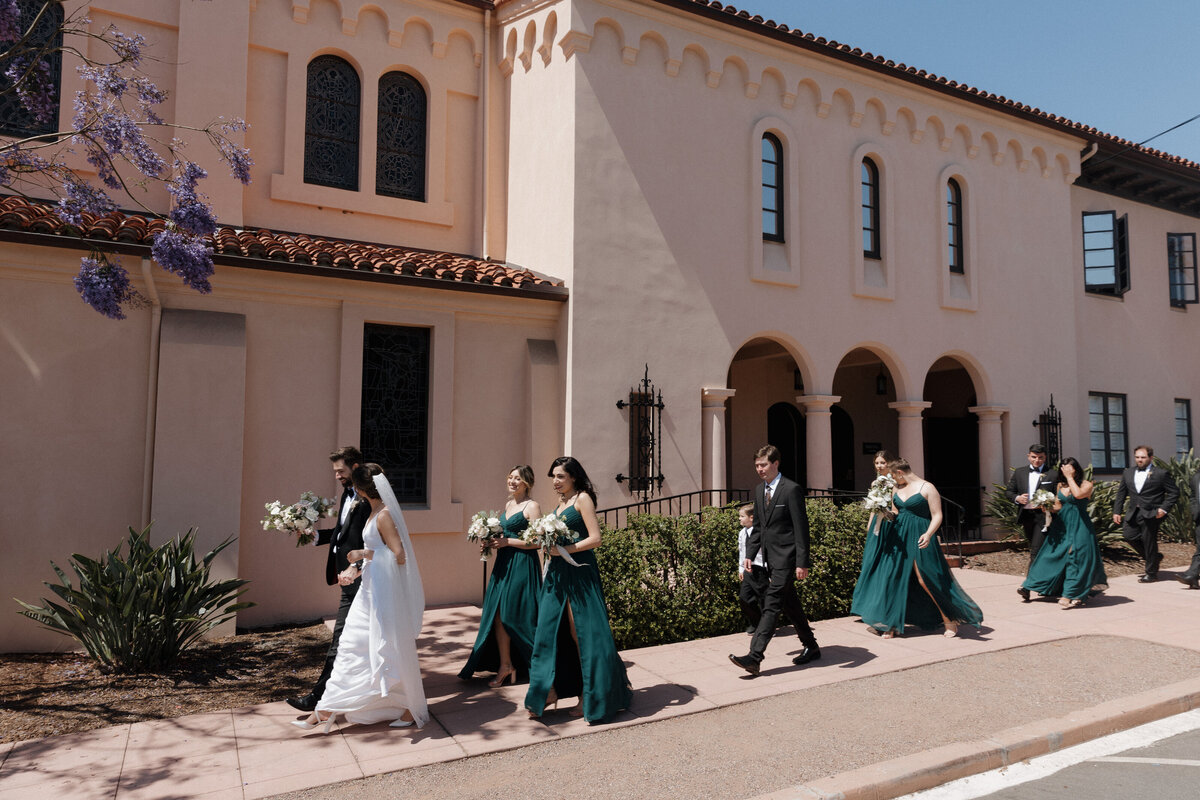 Bride and groom walking with their bridal party outside Cuvier Club in La Jolla, San Diego, during a luxury wedding photography session.