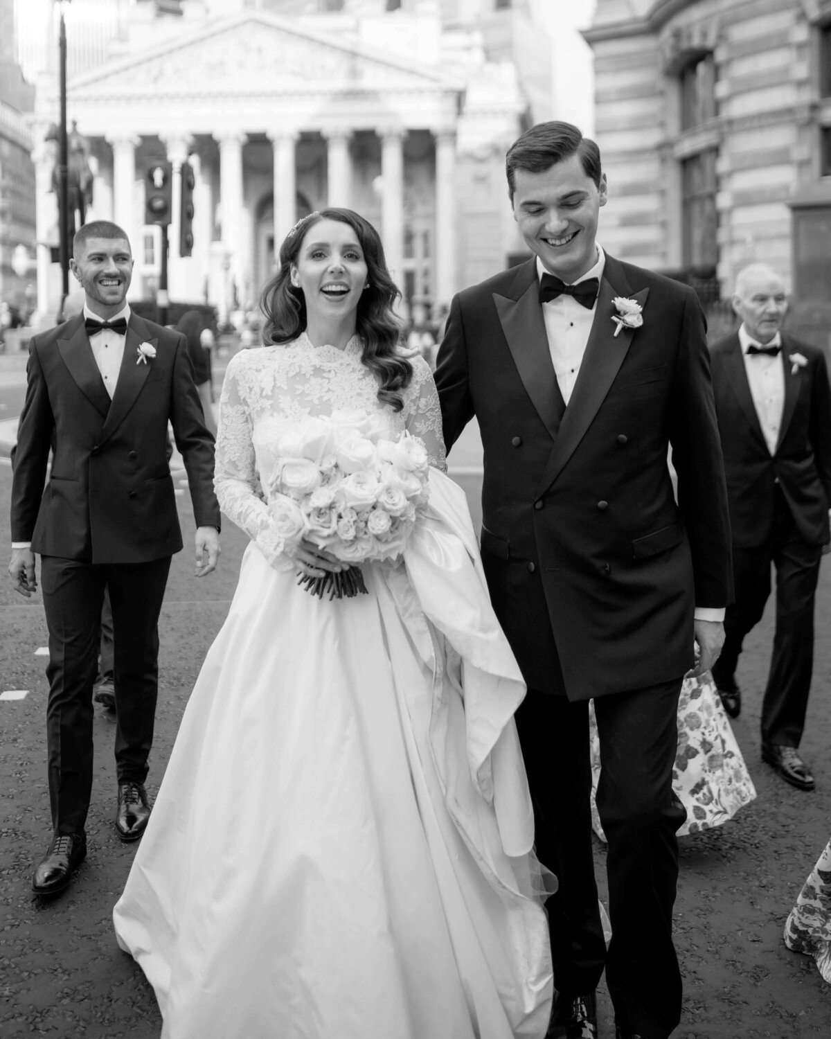 bride and groom walk with their bridal party through the streets of london laughing as they head to their luxury wedding reception at the ned hotel