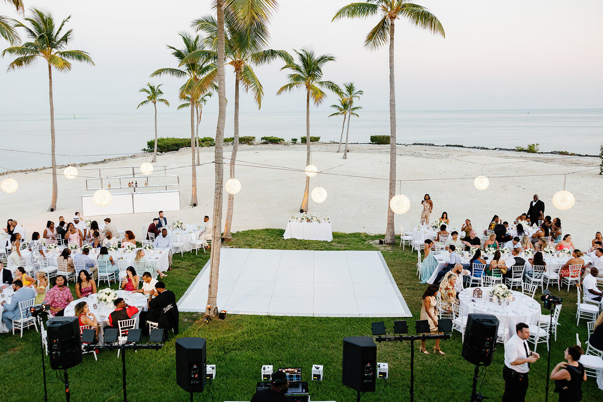 A breathtaking oceanfront wedding ceremony setup with palm trees, lanterns, and a scenic waterfront view at Table Key, Islamorada. Captured by Claudia Amalia Wedding Photography.