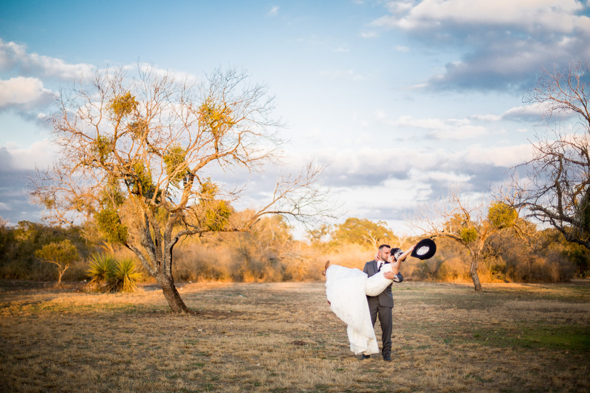 groom carrying bride in field at Hoffman Ranch wedding venue right outside San Antonio