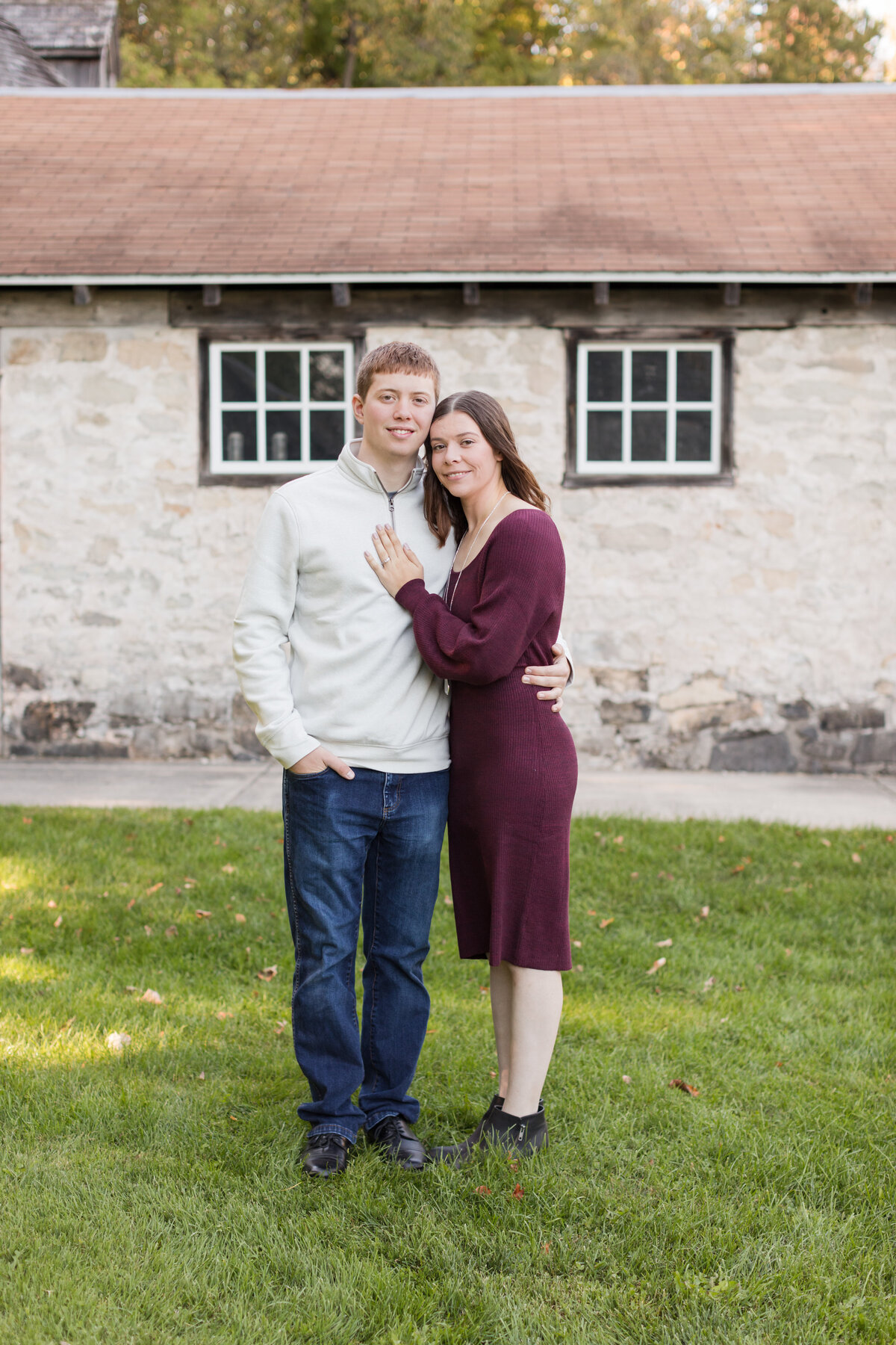 Engaged couple is standing in front of a building and smiling at the camera